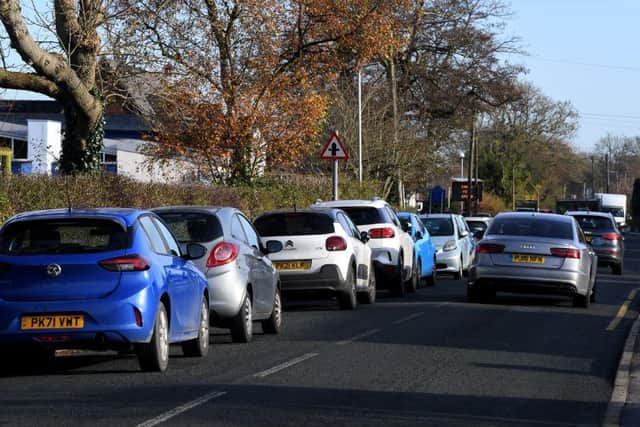 The parked cars causing traffic problems outside the school.