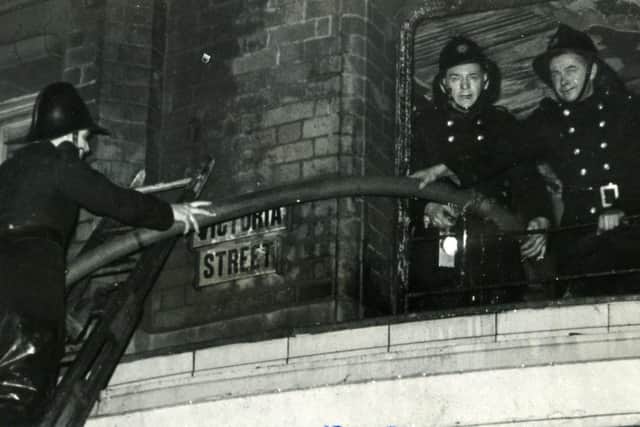 Firemen pull a hose from the top of a fire escape through a Tower building window at the corner of Victoria Street during the fire.