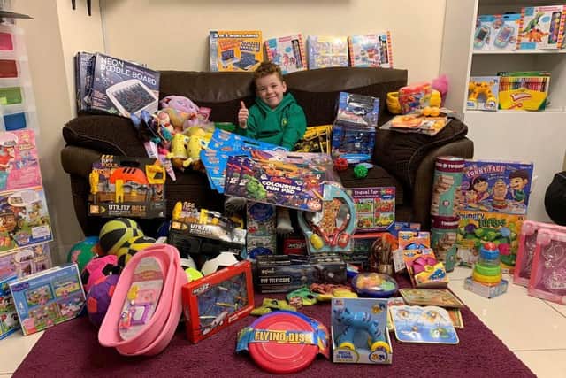Eight-year-old Kian Devine with the many toys for kids less fortunate at Christmas.