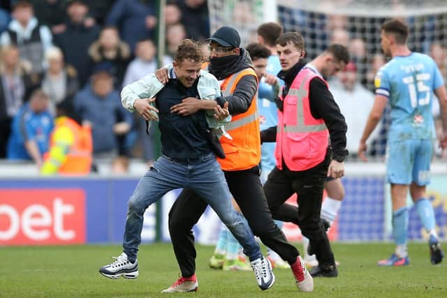 A supporter is apprehended by stewards after invading the pitch during Preston North End's 1-1 draw with Coventry City at the Coventry Building Society Arena in February