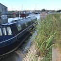A canal boat tilted in low water on the Glasson branch of the Lancaster Canal's approaching Glasson Marina.