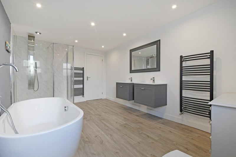 A generously sized family bathroom, there’s a suite in white, which comprises of a low-level WC and two wall mounted wash hand basins with chrome mixer taps and storage beneath. Also, there’s a freestanding bath with a chrome mixer tap and a hand shower facility. To one corner, there’s a walk-in shower enclosure.