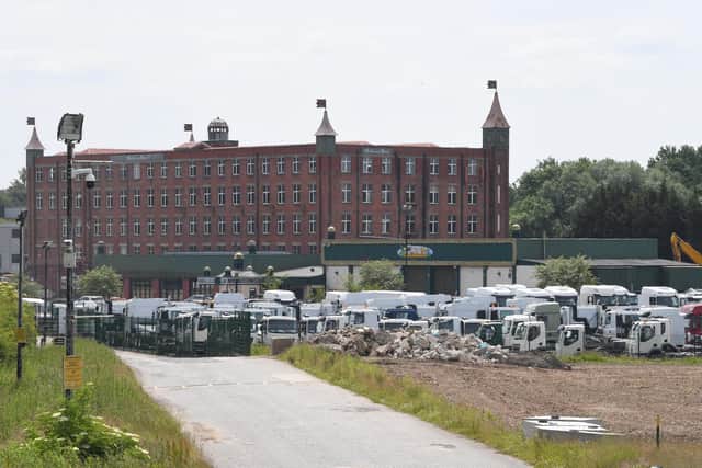Lorries sit in the shadow of the Botany Bay mill building while they wait to be fitted with parts held up in the supply chain