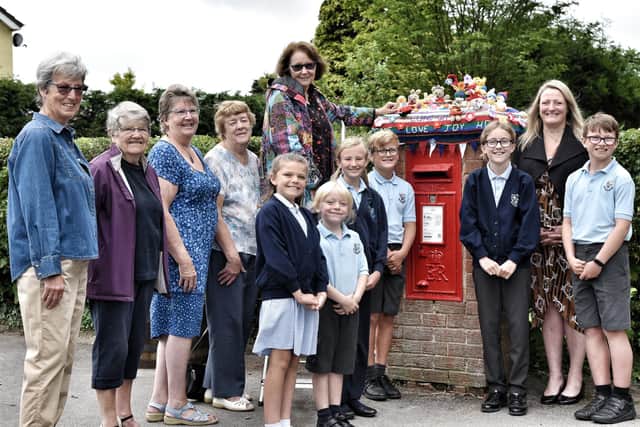 Pictured left, Jane Murden, Pam Metcalf, President Anne Armstrong, Rosey Webster and Anne Horne, some of The Women's Institute who have knitted a bright topper for the post box opposite Newton Bluecoat Church of England Primary School, Newton with Scales, pictured with pupils and head teacher Mrs Robinson.