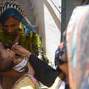 A health worker administers polio vaccine drops to a child during a door-to-door polio vaccination campaign