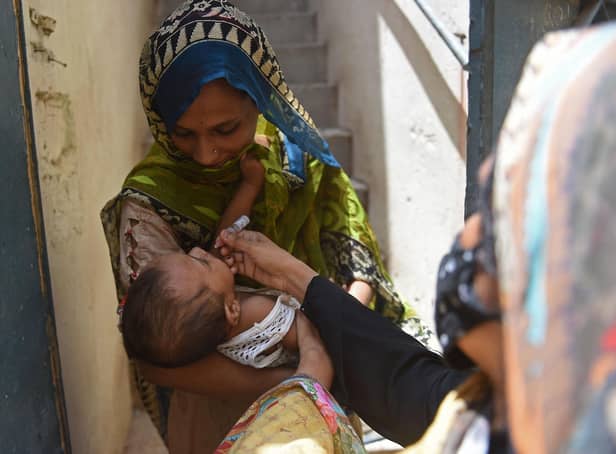 A health worker administers polio vaccine drops to a child during a door-to-door polio vaccination campaign