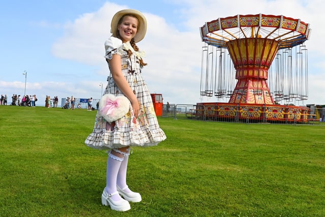 A girl dressed in vintage clothing near the carousel at the vintage festival in Morecambe.