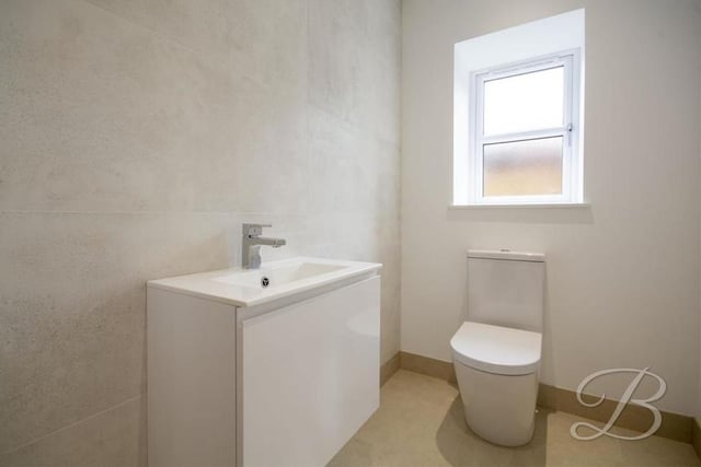 The downstairs toilet features a wall-hung vanity unit, low-flush WC and opaque window to the side.