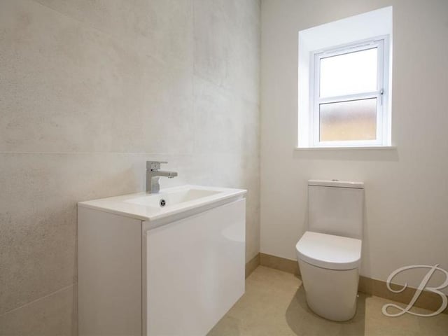 The downstairs toilet features a wall-hung vanity unit, low-flush WC and opaque window to the side.