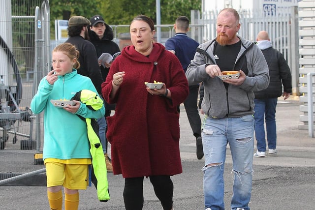 Three arriving fans take advantage of the food vans around the ground.