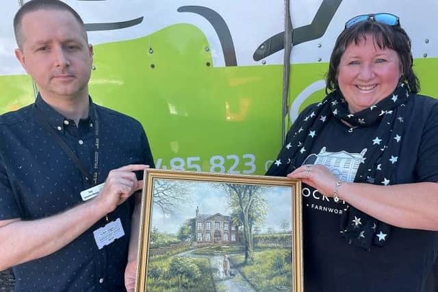 Derian House assistant shop manager, Tony Smalley  reunites a 90-year-old painting with Jayne  Allman of Banana Enterprise Network after it went missing and was later found on the charity shop's eBay site