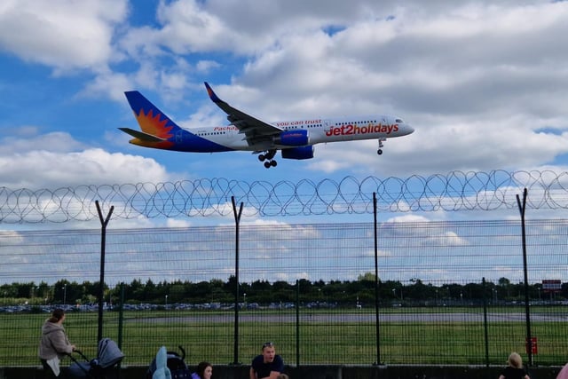 A plane prepares to land as people watch on in the beer garden