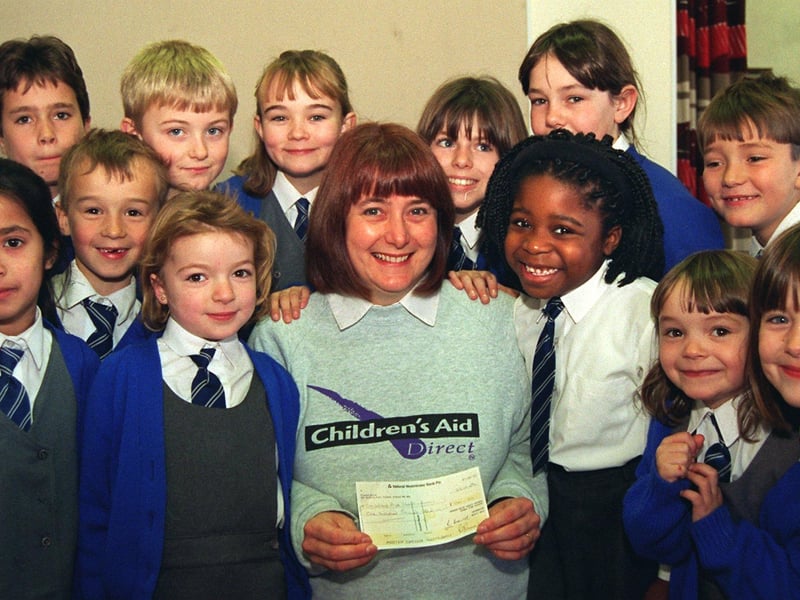 Pat Parker of Childrens Aid receives a £100 cheque from pupils of Queens Drive Primary School who raised the money with a non-uniform day
