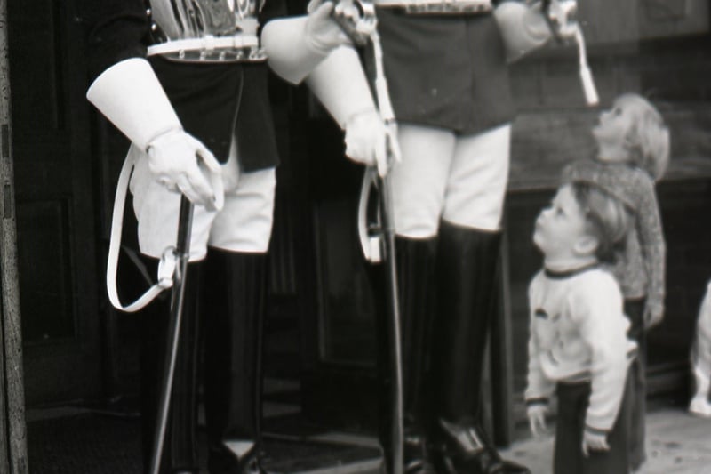 What's going on here? Keith Thomas, aged two and a half, and his pal Ian Crabtree, four, were a little overawed by Trooper Terry Booth of the Life Guards and Cpl. Ian Dane of the Blue and Royals when they came face-to-face at Fulwood Barracks