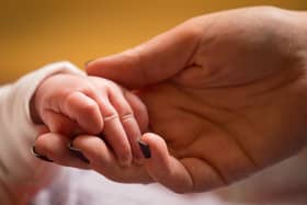 A mother holds the hand of a new baby. PIC: Dominic Lipinski/PA Wire