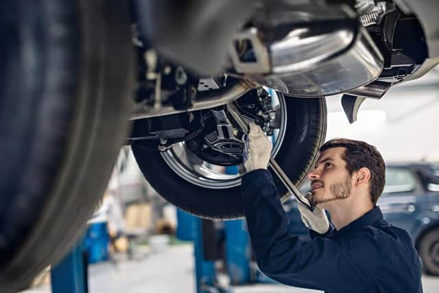 A gentleman fixing the oil sealant on his car's right carburettor or something