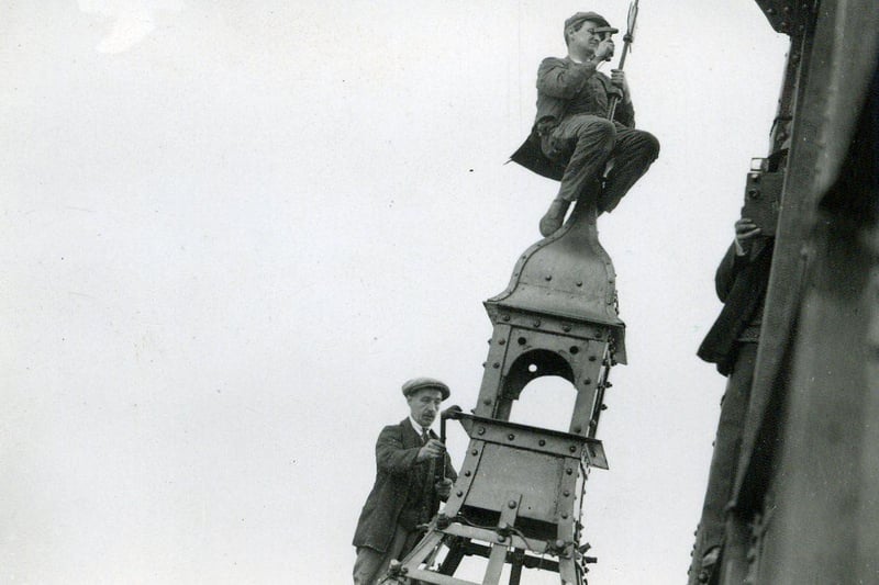 Perched precariously at such a height, these workmen are putting the finishing touches to the top of the Tower