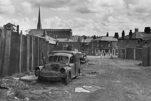A typical scene in run-down Preston, with abandoned cars just sat waiting to be eventually scrapped. In the distance you can see the towering spire of St Walburge's Church