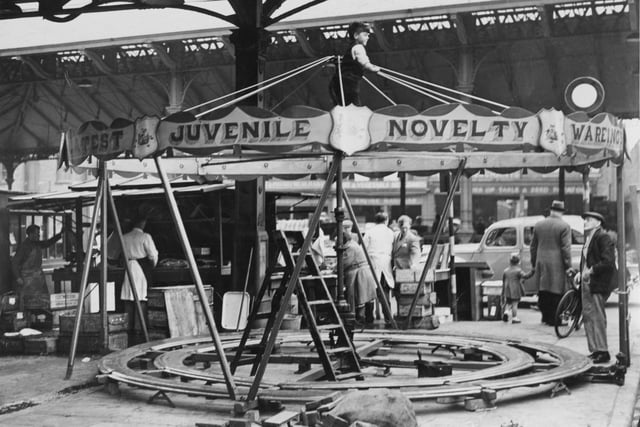 Setting up for the Preston Whitsuntide Fair at the covered market, taken in 1950. Note the young boy perched at the top of the carousel!