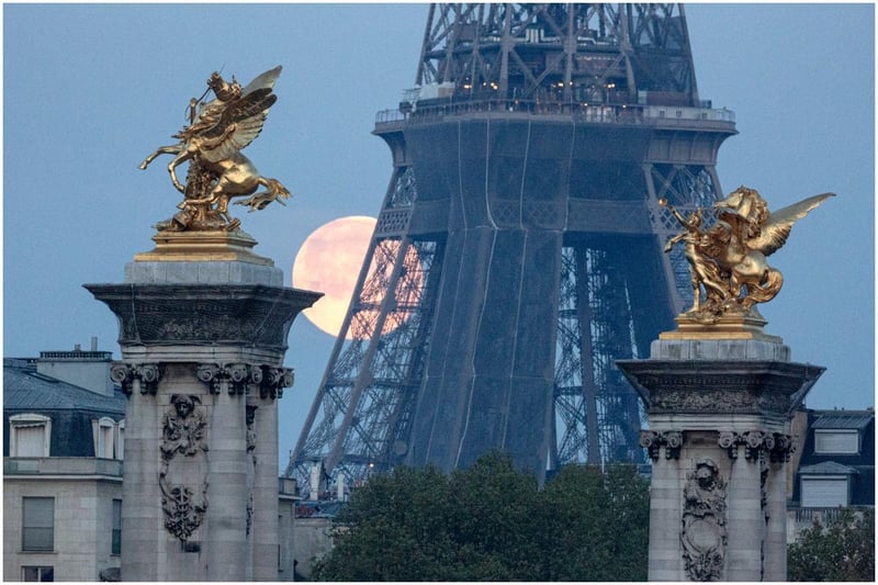 A supermoon sets behind the Eiffel Tower and statues of Pegasus Held By Fame on the Pont Alexandre III bridge (Getty Images)
