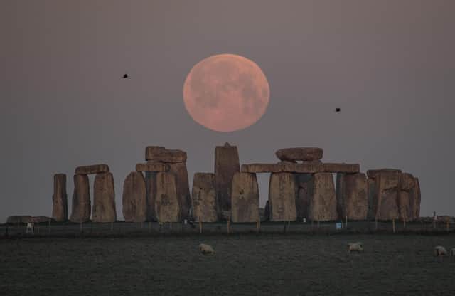 The full moon sets behind Stonehenge in Amesbury, England. (Photo by Finnbarr Webster/Getty Images)