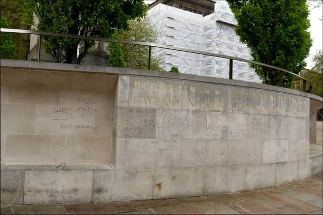 The wall around the war memorial daubed with graffiti.