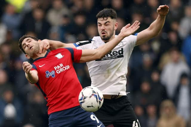 Preston North End striker Ched Evans and Derby County's Eiran Cashin battle for the ball