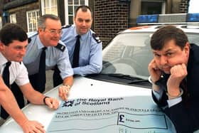 Peter Taylor from the Preston and North Lancashire Blind Welfare Society eventually smiled when the local police (left to right) Inspector Mark Tottman, Community Officer for the Kingsfold area Peter Rigby and Sgt. Alan Roberts from Penwortham Police Station took the handcuffs off and presented him with a cheque for 550 raised at a recent 60s and 70s night 