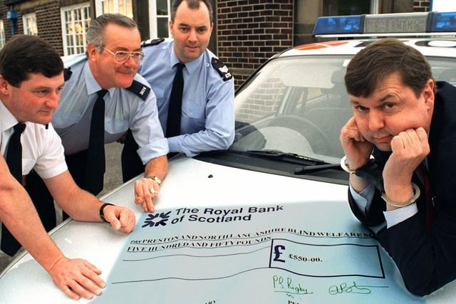 Peter Taylor from the Preston and North Lancashire Blind Welfare Society eventually smiled when the local police (left to right) Inspector Mark Tottman, Community Officer for the Kingsfold area Peter Rigby and Sgt. Alan Roberts from Penwortham Police Station took the handcuffs off and presented him with a cheque for 550 raised at a recent 60s and 70s night
