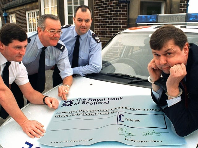 Peter Taylor from the Preston and North Lancashire Blind Welfare Society eventually smiled when the local police (left to right) Inspector Mark Tottman, Community Officer for the Kingsfold area Peter Rigby and Sgt. Alan Roberts from Penwortham Police Station took the handcuffs off and presented him with a cheque for 550 raised at a recent 60s and 70s night