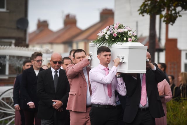 Family and friends help carry the white coffin