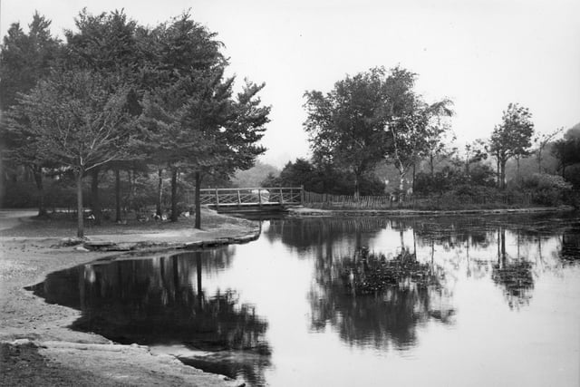 A charming view of a corner of the lake and rustic bridge in Haslam Park, Ashton