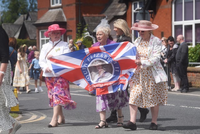 The procession began at noon, with crowds lining the village streets to watch the brass band, dancers, floats, and vintage cars and penny farthing bicycles pass by.