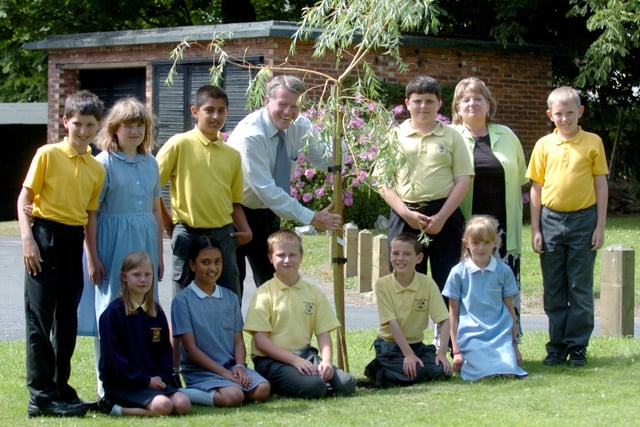 Keith Johnson planting a tree at Fulwood and Cadley Primary School, watched by some of the pupils at the school