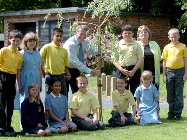 Keith Johnson planting a tree at Fulwood and Cadley Primary School, watched by some of the pupils at the school