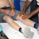 A medical student feeling a man's knee as part of their medicine and surgery course