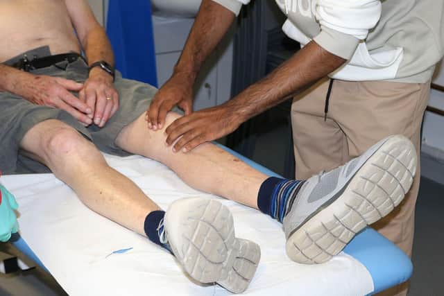 A medical student feeling a man's knee as part of their medicine and surgery course