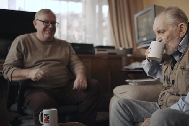 Volunteer Liam (left) with blind veteran Ken enjoying a cup of tea and a chat. Photo:  Blind Veterans UK