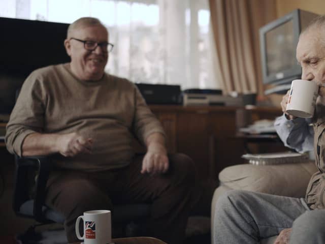 Volunteer Liam (left) with blind veteran Ken enjoying a cup of tea and a chat. Photo:  Blind Veterans UK