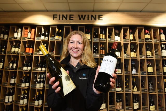 Staff member Liz Fleming with fine wines section in the store