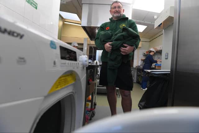 Site supervisor Nigel Malyon using the school's washing machine to clean pupils' uniforms.