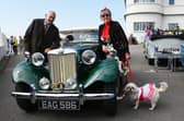 A man, a lady and a dog all in vintage clothing next to a vintage MG car at the vintage festival at the weekend.