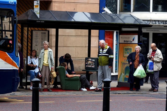Two men watching television at a bus stop on Fishergate in Preston after British Gas transformed it to publicise their Win A Home competition