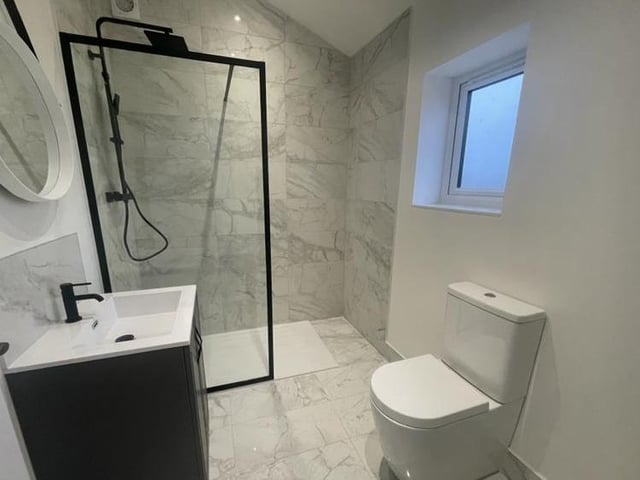 The shower room oozes style. It is fitted with a contemporary suite, comprising walk-in shower enclosure, wash hand basin set in a vanity-style unit, low-flush WC and ladder-style radiator. The floors and walls are tiled.