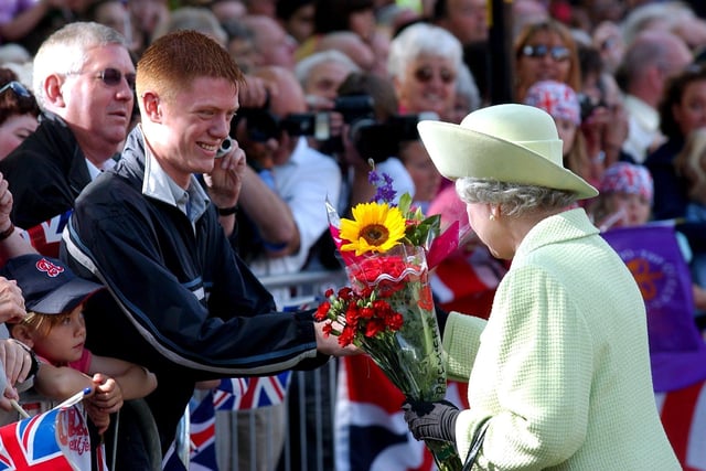 Ben Davies, who was 17, presents the Queen with flowers during her visit to Preston in 2002