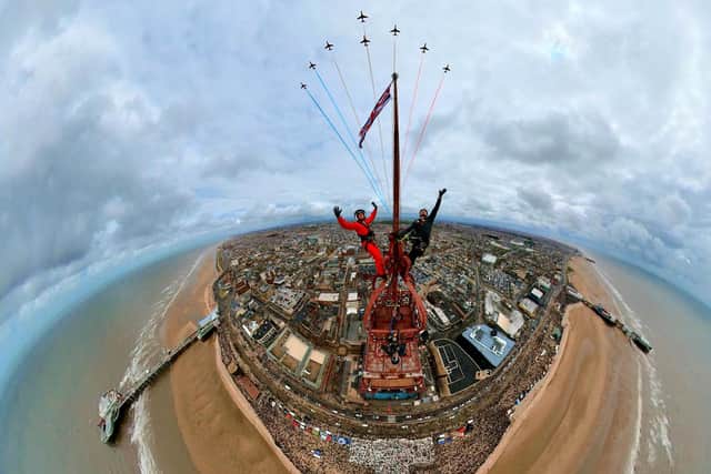 Two thrill-seekers scaled the 518ft Blackpool Tower for a selfie with a Red Arrows display. Adam Collins, Officer Commanding the Red Arrows, was at the top of the flag pole on the tower saluting them as they flew past. See SWNS story SWMRtower.