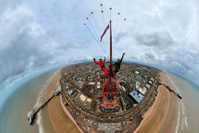 Two thrill-seekers scaled the 518ft Blackpool Tower for a selfie with a Red Arrows display. Adam Collins, Officer Commanding the Red Arrows, was at the top of the flag pole on the tower saluting them as they flew past. See SWNS story SWMRtower. 