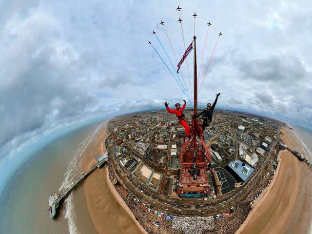 Two thrill-seekers scaled the 518ft Blackpool Tower for a selfie with a Red Arrows display. Adam Collins, Officer Commanding the Red Arrows, was at the top of the flag pole on the tower saluting them as they flew past. See SWNS story SWMRtower. 