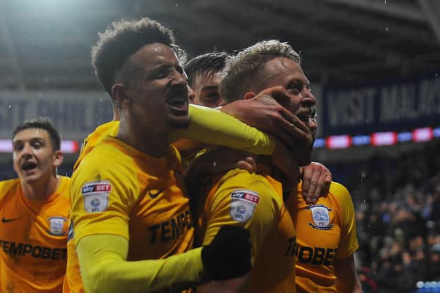 Tom Clarke is mobbed by his Preston North End team-mates at Cardiff City