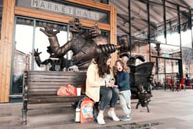 Mother and child sit on the Wallace and Gromit bench outside Preston Markets